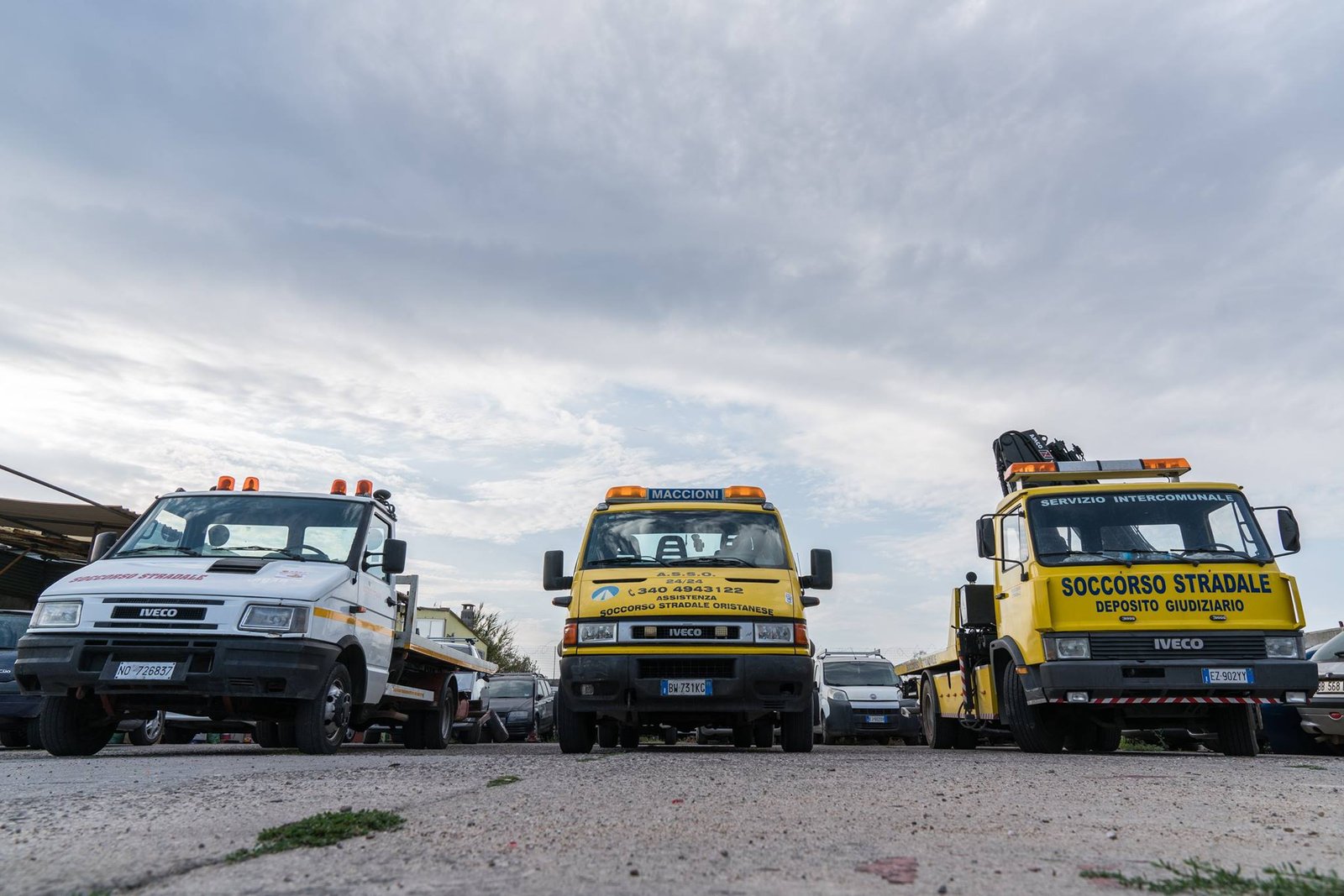 Tre carroattrezzi Iveco, uno bianco e due gialli con scritte A.S.S.O. e Deposito giudiziario, in un piazzale
